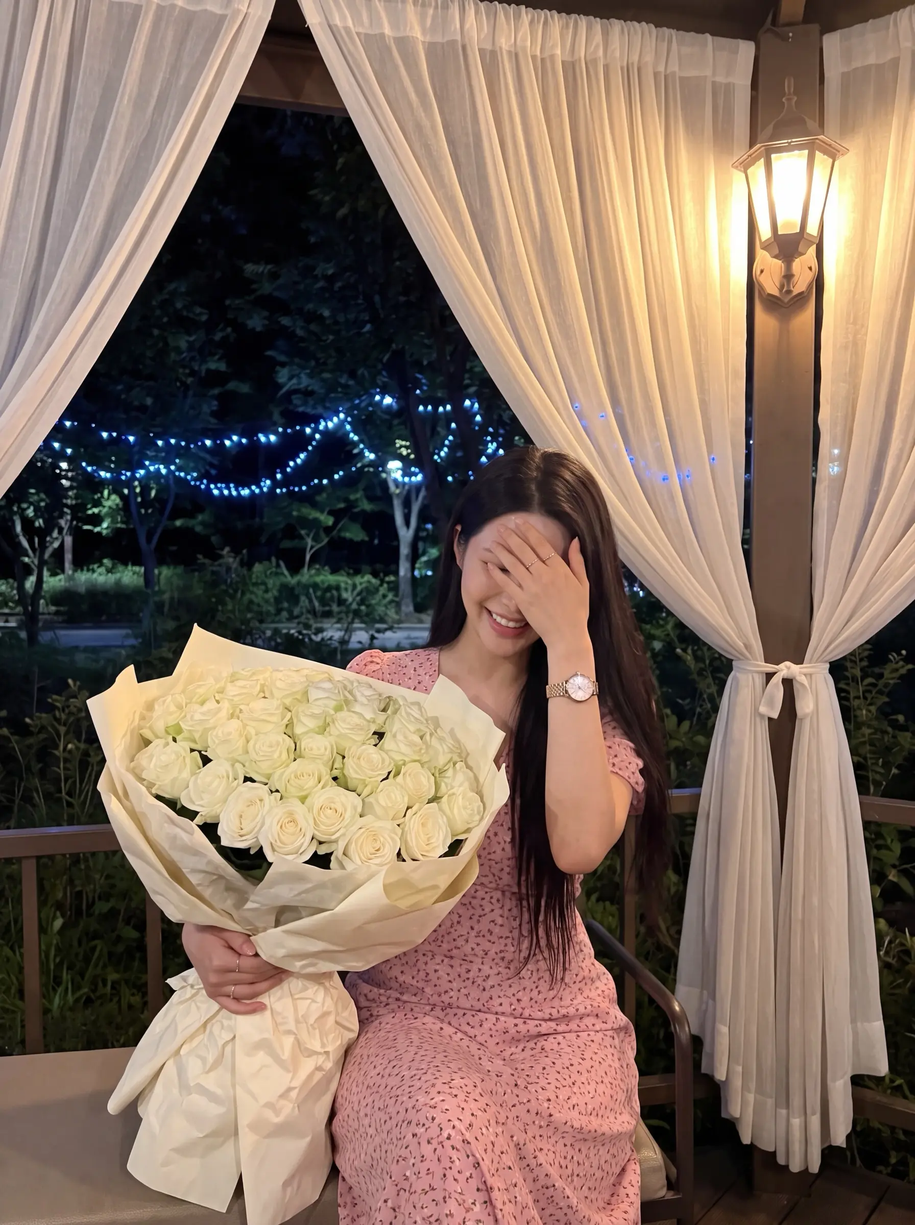 Woman laughing behind her hand while holding a large bouquet of white roses